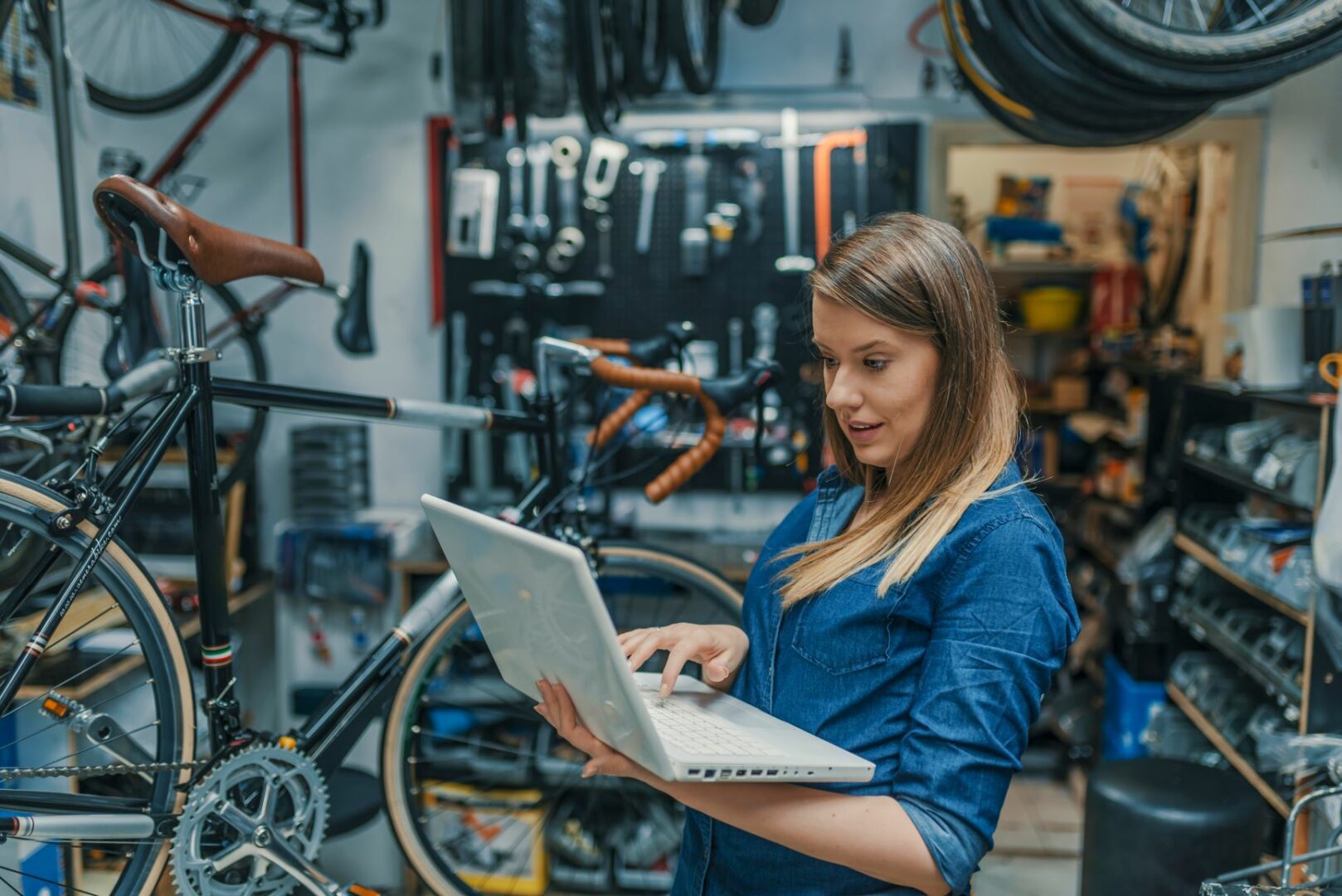 een ondernemer met laptop in haar fietsenwinkel